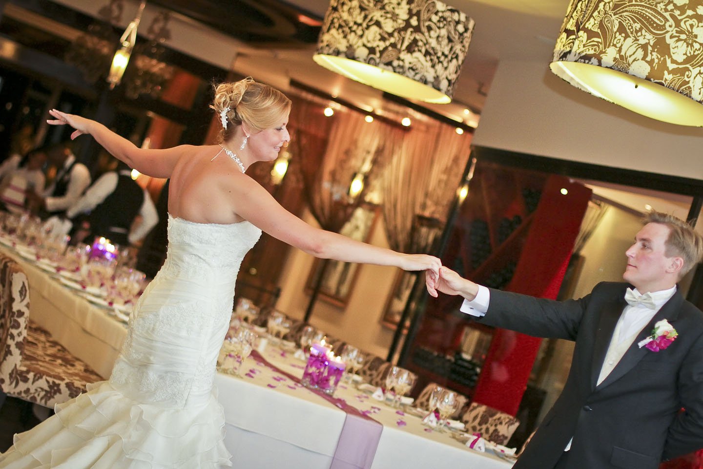 Wedding couple in an open hold, standing apart, facing each other during their dance.