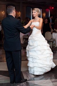 Newlyweds lovingly hold hands, facing each other in the midst of their wedding dance routine, symbolizing their unity and love.