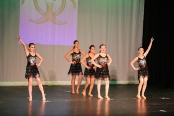 Group of students performing a dance routine on a stage at a competition