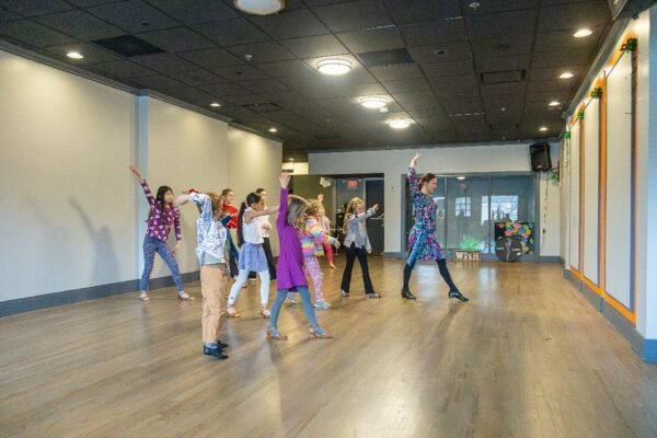 Kids aged 3 and up participating in a free trial dance class at Moonlight Ballroom Dance Studio, learning dance techniques in a bright, welcoming studio environment